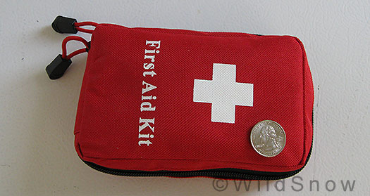 Backcountry skiing first aid kit, closed up, with coin for scale.