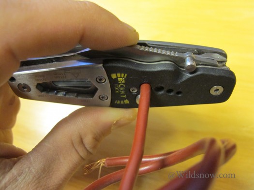 The included wire stripper uses four holes labeled for 16, 14, 12, and 10 AWG wire. To strip a wire, you open the knife blade, insert the wire in the proper hole, and close the knife blade partially so that it presses on the insulation. Pressing down lightly on the blade you rotate the wire to cut around the insulation.