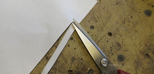 Incredibly sophisticated adjustment tool is carefully cut from paper, about a centimeter wide.