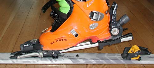 Naxo binding in touring mode, showing double toe pivot at first stage of stride. The double pivot allows a somewhat natural stride, but more, it allows the use of a full size alpine-like toe. The binding weighs about the same as a Diamir Freeride, and is sold with brakes. Heel lifter is designed so that the binding can not accidentally switch to touring mode while alpine skiing -- a concern of some hard cores.