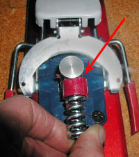 Dynafit heel with housing removed, spring and thimble bushing held in operative position. Arrow indicates where edge of aluminum post wears into bushing.
