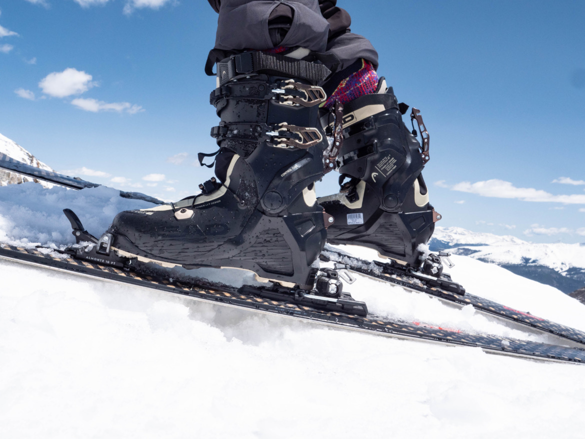 Head Crux backcountry ski boots on Head skis on top of a snowy ridge on a sunny day with blue skies