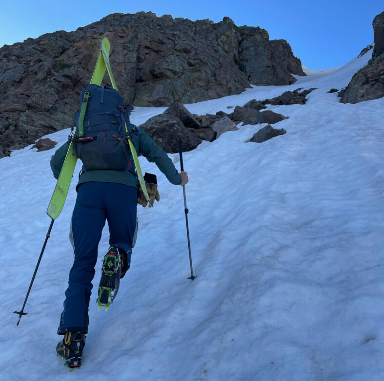 skiers climbing a steep slope wearing crampons on La Sportiva Skorpius II boots with skis on his back 