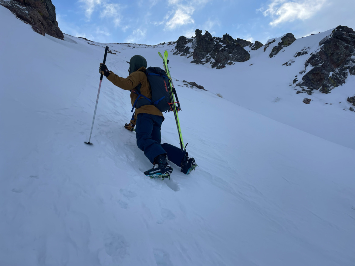 skier bootpacking steep slope wearing Scarpa F1 XT backcountry ski boots equipped with boot crampons