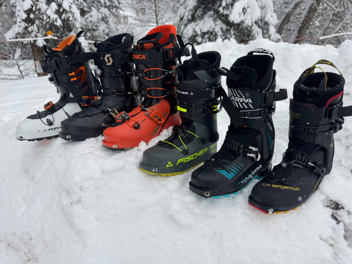 several models of backcountry ski boots lined up in the snow