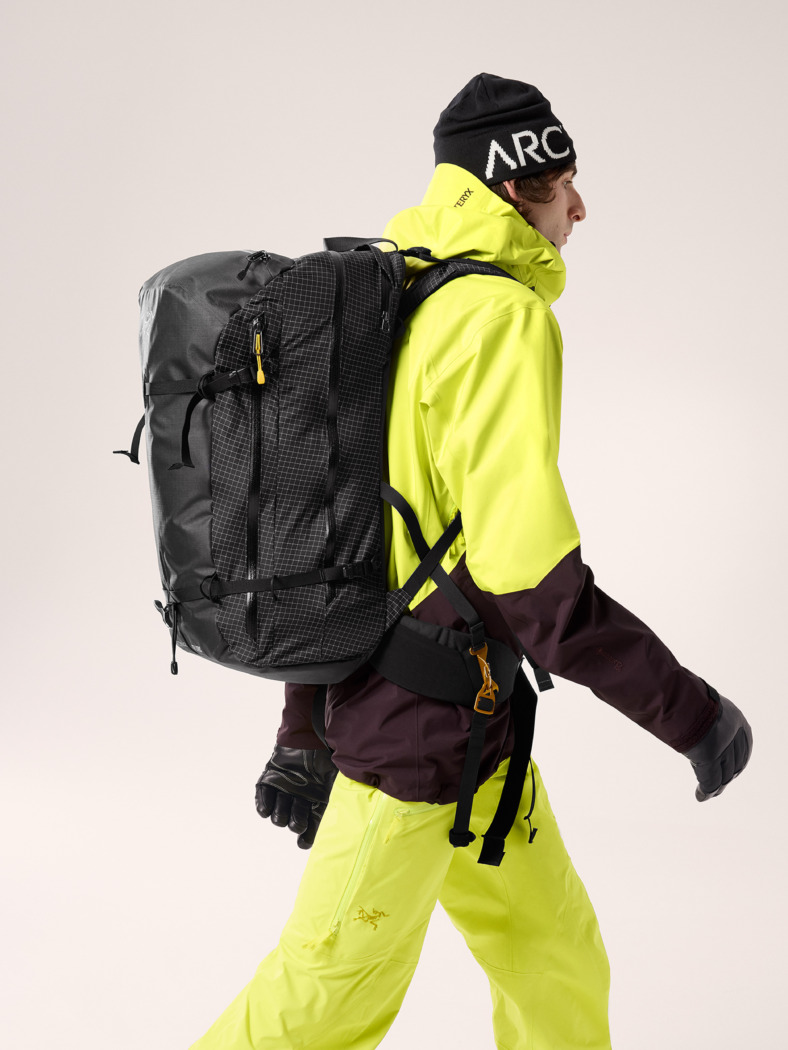 product shot of model in yellow ski clothes walking wearing the Arc'teryx Micon LiTRIC 42 airbag backpack