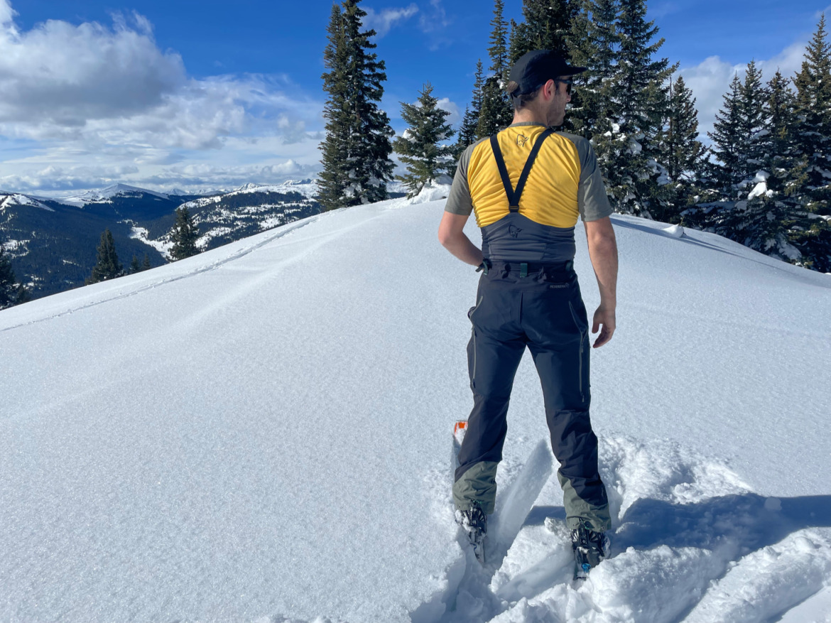 Backcountry skier with back to the camera wearing lightweight touring bib pants.