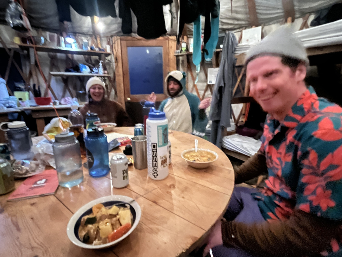 People sitting around a table eating in a backcountry hut