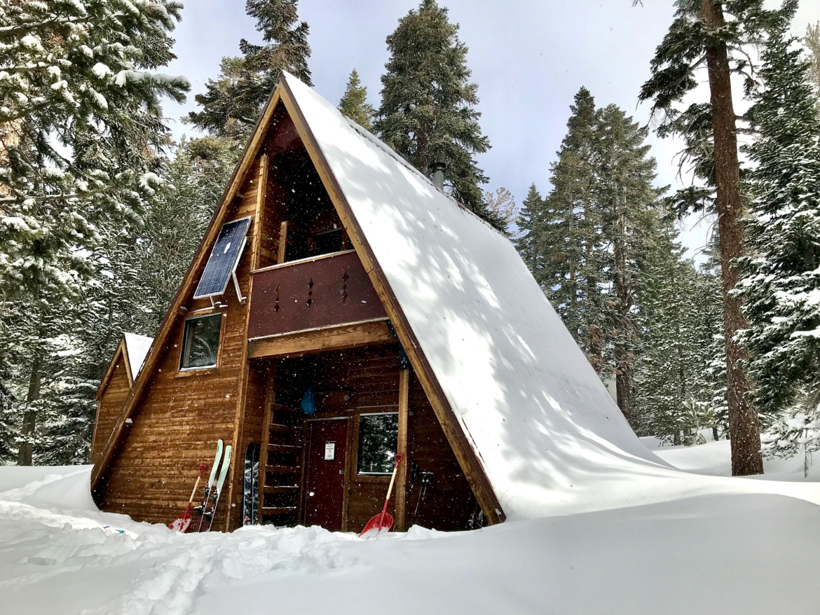 A-frame backcountry ski hut covered with snow.