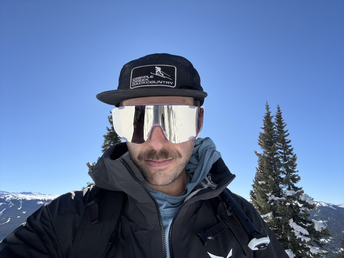 skier in a cap wearing oversized touring sunglasses with mirrored lenses