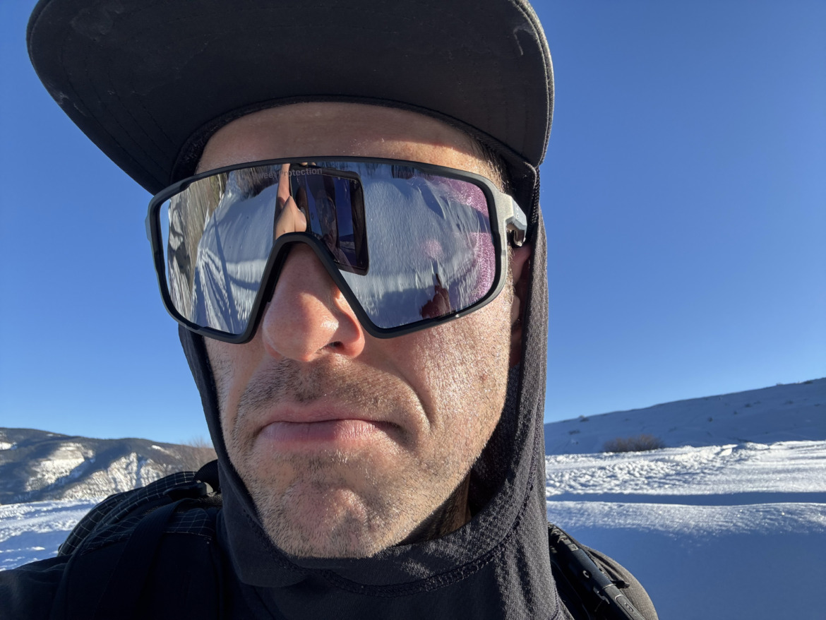 close-up of skier in ball cap wearing oversized sunglasses