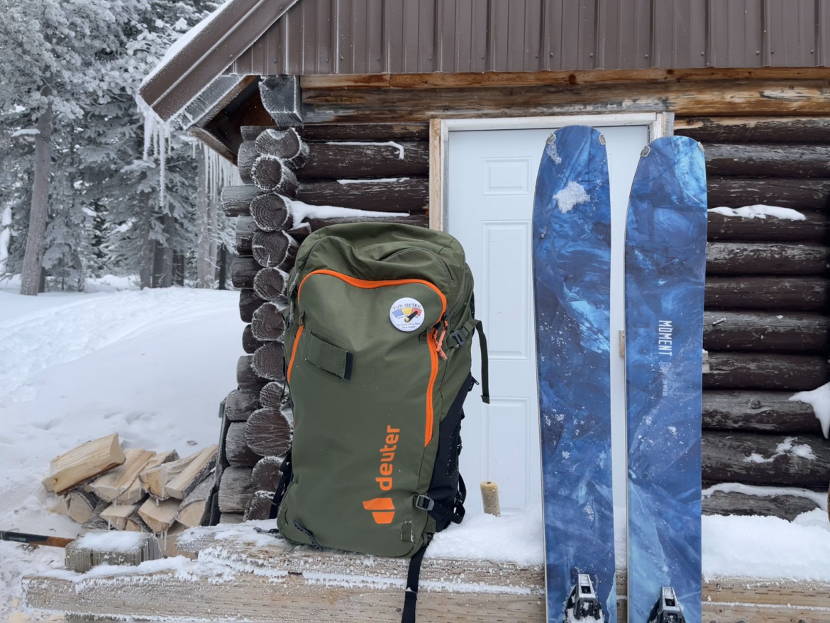 skis and backpack sitting outside wooden building