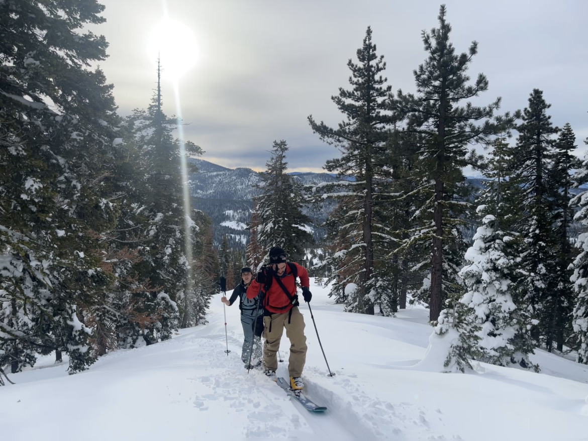 backcountry skiers climbing up with sun in background